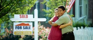 Happy couple hugging by "Sold" sign